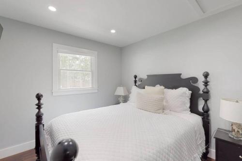 a bedroom with a bed with white sheets and a window at Brand new house with an all year round hot tub. in Westhampton Beach