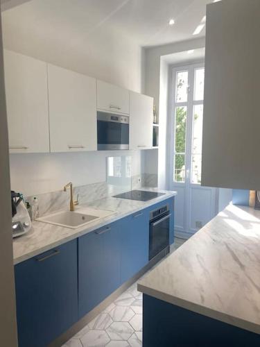 - une cuisine avec des placards bleus et blancs et un évier dans l'établissement Appartement de standing vue mer, à Marseille
