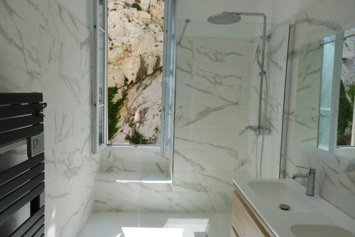 une salle de bain blanche avec une douche et un lavabo dans l'établissement Appartement de standing vue mer, à Marseille