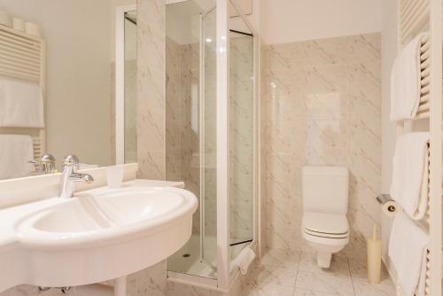 La salle de bains blanche est pourvue d'un lavabo et de toilettes. dans l'établissement Villa Magnolia - Boutique Superior Rooms, à Locarno