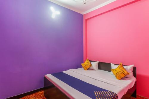Kākori的住宿－OYO 78880 Rajdhani Hotel，卧室设有粉红色和紫色的墙壁和一张床