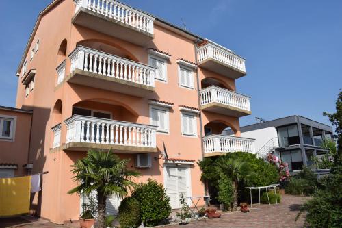 un edificio rosa con balcones blancos. en Apartments Lavanda, en Crikvenica