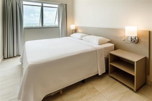 a bedroom with a large white bed and a window at Salinas park resort in Salinópolis