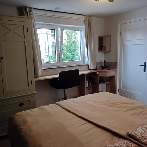 um quarto com uma cama, uma secretária e uma janela em B&B Keukja Cuijk em Cuijk