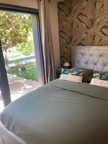 une chambre avec un lit et une grande fenêtre dans l'établissement A lombre du magnolia, à LʼIsle-sur-la-Sorgue