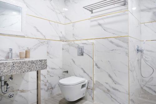 a white bathroom with a toilet and a sink at Okean Apartments in Ierissos