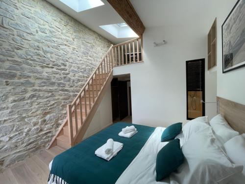 ein Schlafzimmer mit einem Bett und einer Steinmauer in der Unterkunft Le Repaire du Pic, gîte de charme 3 étoiles in Notre-Dame-de-Londres