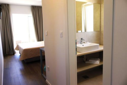 a bathroom with a sink and a bed and a mirror at VILLA CALA, Hotel Rooms&Apartments in Novalja