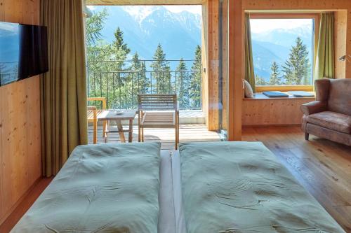 a bed in a room with a view of a balcony at Hotel Waldhaus in Bettmeralp