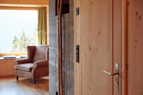 a door to a room with a chair and a window at Hotel Waldhaus in Bettmeralp
