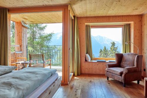 a bedroom with a bed and a chair and a window at Hotel Waldhaus in Bettmeralp