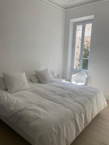 un lit blanc dans une chambre blanche avec une fenêtre dans l'établissement Appartement de standing vue mer, à Marseille