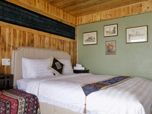 - une chambre avec un grand lit blanc et des murs en bois dans l'établissement Ta Phin Cottage, à Sa Pa
