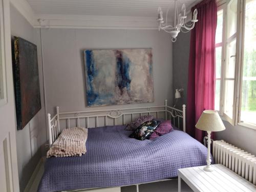 a bedroom with a bed with purple sheets and pink curtains at Villa Anna in Lahti