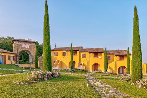 ein großes gelbes Gebäude mit Bäumen im Hof in der Unterkunft Borgo del Faggio - Case Vacanza in Montepulciano