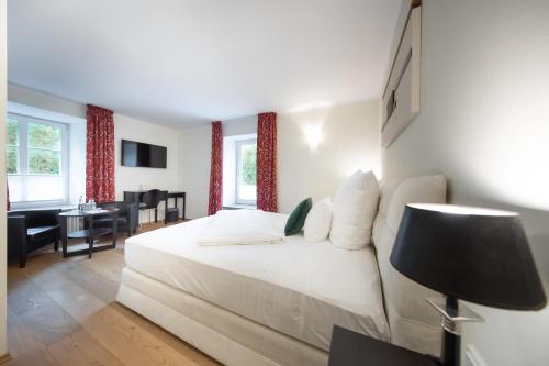 a bedroom with a white bed and a living room at Die LÜ - Lüttelforster Mühle in Schwalmtal