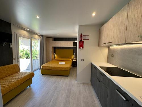 マリーナ・ディ・ビッボーナにあるCamping I Melograniのベッド1台付きの部屋、ソファ付きのキッチンが備わるアパートメントです。