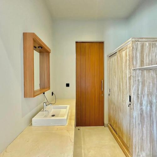 a bathroom with a sink and a wooden door at Mega Canggu Guest House in Canggu