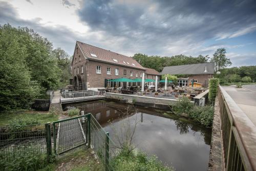 a building with a restaurant next to a river at Die LÜ - Lüttelforster Mühle in Schwalmtal
