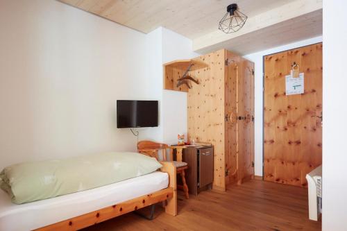 a bedroom with a bed and a tv on a wall at Hotel Waldhaus in Bettmeralp