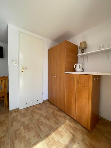 a small kitchen with wooden cabinets and a door at Pokoje gościnne u Małgosi in Jarosławiec