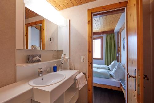 a bathroom with a sink and a mirror and a bed at Hotel Waldhaus in Bettmeralp