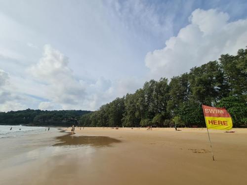 a sign on a beach with people in the water at The Naithorn Condo Unit 401 in Nai Thon Beach