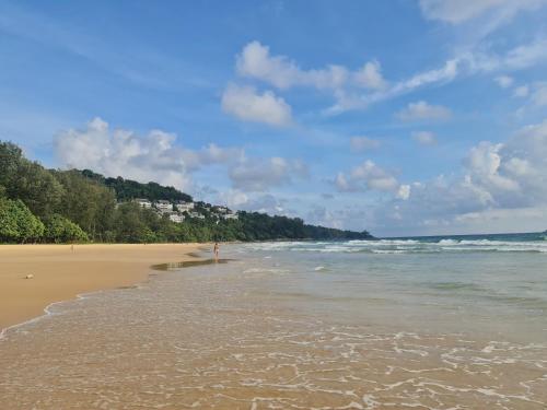 a sandy beach with trees and the ocean at The Naithorn Condo Unit 401 in Nai Thon Beach