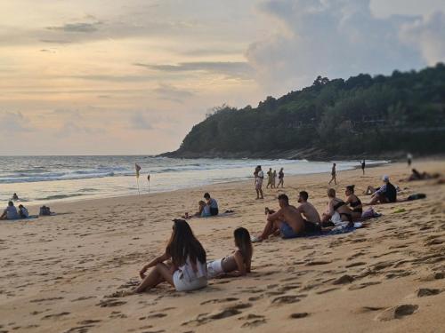 a group of people sitting on the beach at The Naithorn Condo Unit 401 in Nai Thon Beach
