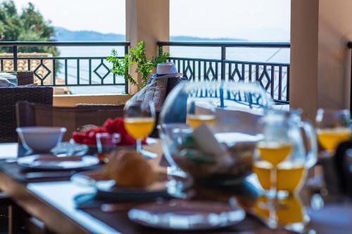 a table with glasses of wine on a balcony at Beach villa Aetos kaminaki Nissaki in Nisakion