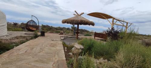 a walkway with a straw umbrella and a bench at Ak-Tengir Yurt Resort in Tossor