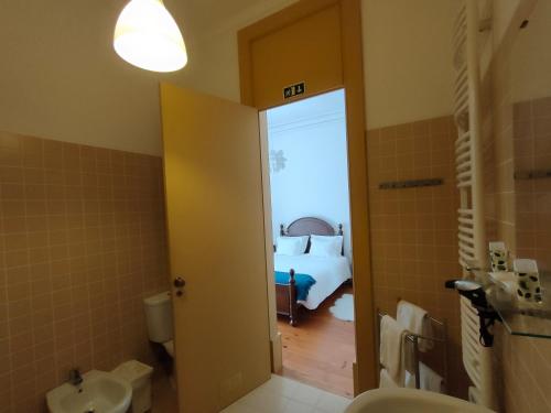 a bathroom with a sink and a bedroom with a bed at A Vianesa - Guest House in Viana do Castelo
