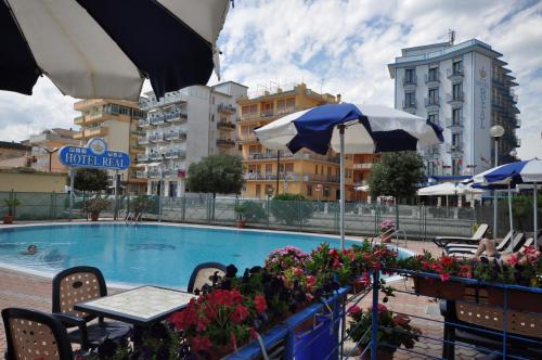 a swimming pool with tables and chairs and umbrellas at Hotel Real in Sottomarina