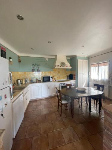 une cuisine avec une table, des chaises et un réfrigérateur dans l'établissement Maison de campagne en Provence, à Barbentane
