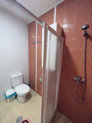 a bathroom with a toilet and a shower with red tiles at Paradise Sol Apartamento en Los Alcázares in Los Alcázares