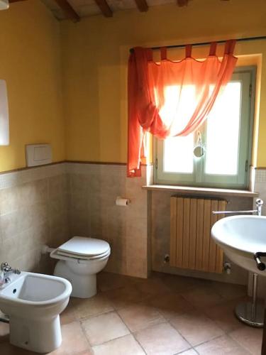 a bathroom with a toilet and a sink and a window at Dependance - Casa delle rondini in Carignano