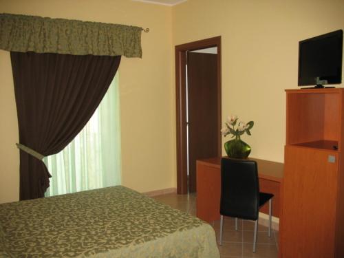 - une chambre avec un lit, un bureau et une télévision dans l'établissement Da Santo Hotel Ristorante Pizzeria, à Ferrare