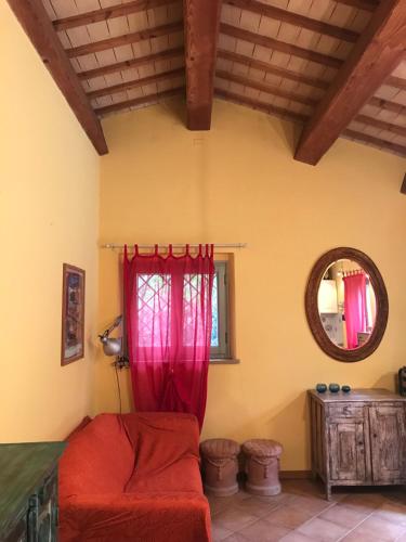 a living room with a red couch and a mirror at Dependance - Casa delle rondini in Carignano