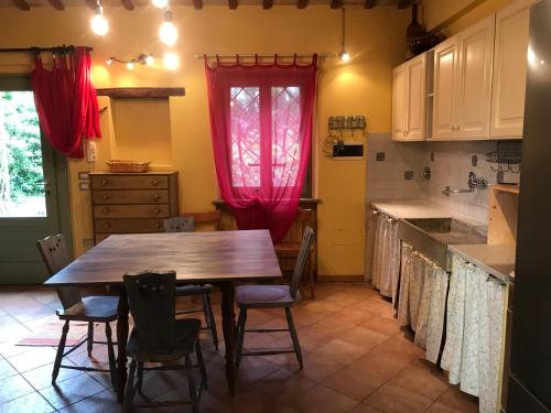 a kitchen with a wooden table and chairs in it at Dependance - Casa delle rondini in Carignano