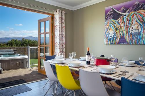 a dining room with a table with chairs and a painting on the wall at Snowmass Lodge - hot tub in Aviemore in Aviemore
