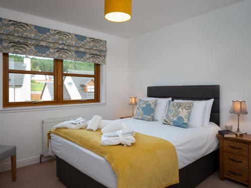 a bedroom with a bed with towels on it at Snowmass Lodge - hot tub in Aviemore in Aviemore