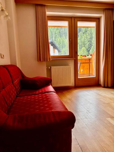 a living room with a red couch and a large window at Residence Aster in Solda