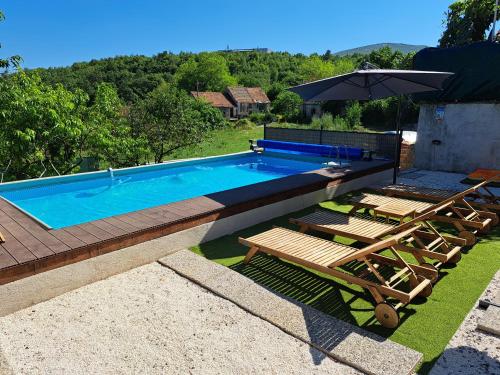 - une piscine avec des chaises et un parasol dans l'établissement Holiday house LUMA, à Hrvace