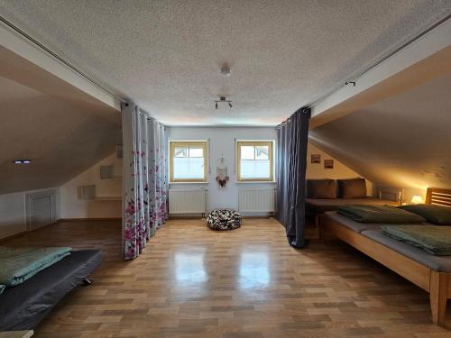a attic room with two beds and two windows at Ferienwohnung nähe Chiemsee (30 Min.) in Unterneukirchen
