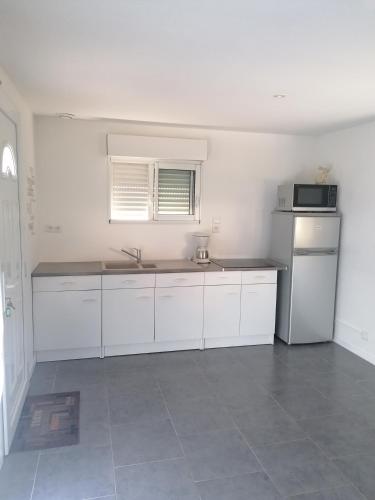 une cuisine blanche avec un évier et un micro-ondes dans l'établissement Appartement indépendant, parking privé, 600m du circuit, à Arnage