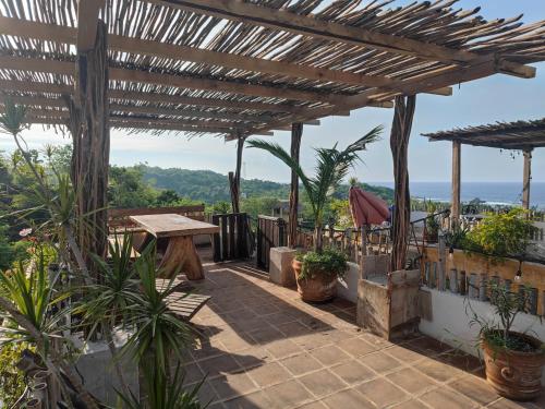 a patio with a wooden pergola and plants at Hotel Quinto Sol in Mazunte