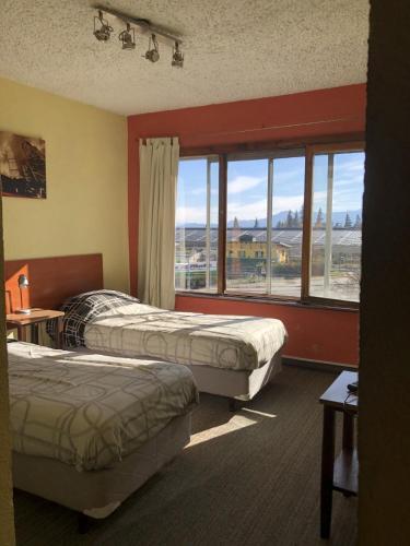 a hotel room with two beds and a large window at Italia Inn Hostel in San Carlos de Bariloche