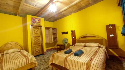 two beds in a room with yellow walls at El Retiro Lanquin in Lanquín