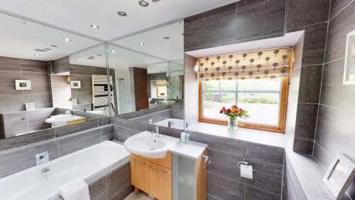 uma casa de banho com uma banheira, um lavatório e um espelho. em The Eagle's Nest em Boat of Garten
