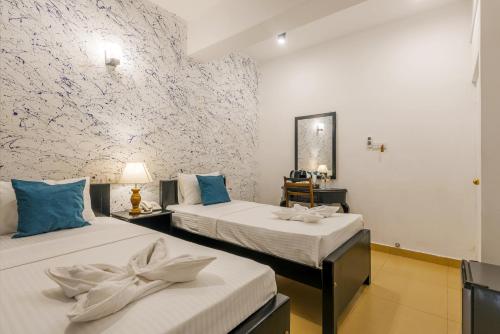 a bedroom with two beds with blue pillows at Beverly Hills Hotel in Mount Lavinia